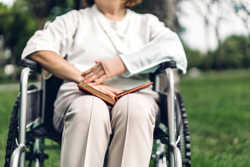 Obraz premium Senior adult elderly asia women sit on wheelchair and reading book outdoor