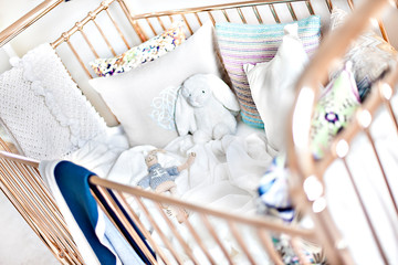 Fototapeta na wymiar Baby bed with pillows and rabbit teddy bears