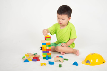 Little Asian toddler boy playing wood blocks wear helmet engineer