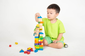Little Asian toddler boy playing wood blocks wear helmet engineer