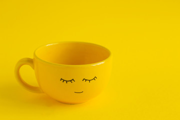 yellow cup with cute smile face on a yellow background