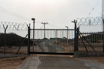 Automatic metal gate. Barbed wire fence block the way. gate to a closed area.