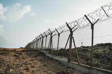 barbed wire steel wall against the immigations. Wall with barbed wire on the border of 2 countries....