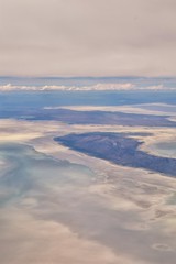 Obraz na płótnie Canvas Aerial view from airplane of the Great Salt Lake in Rocky Mountain Range, sweeping cloudscape and landscape during day time in Spring. In Utah, United States.