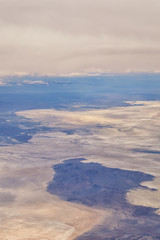 Aerial view from airplane of the Great Salt Lake in Rocky Mountain Range, sweeping cloudscape and landscape during day time in Spring. In Utah, United States.