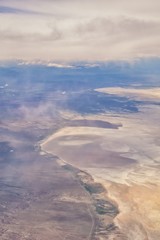 Aerial view from airplane of the Great Salt Lake in Rocky Mountain Range, sweeping cloudscape and landscape during day time in Spring. In Utah, United States.