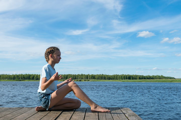 Fototapeta na wymiar girl meditates in nature by the lake on a nice sunny day