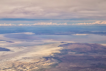 Aerial view from airplane of the Great Salt Lake in Rocky Mountain Range, sweeping cloudscape and landscape during day time in Spring. In Utah, United States.