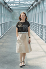 Beautiful stylish woman , smiling, happy, street style, beige skirt, green t-shirt.