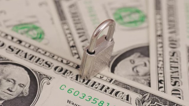 Padlock on dollar bills. Financial frauds concept.
