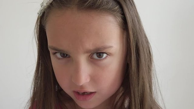 A young girl stares straight at the camera and yells in anger. Slow motion.