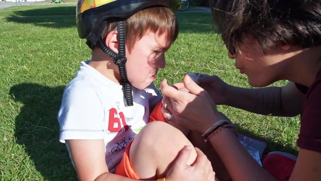 CLOSE UP Footage of a Mother who treats her son's knee after a bike accident 60 fps