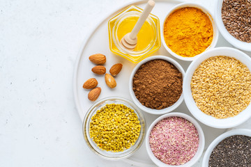 Healthy super food clean eating selection (seeds, powder turmeric, carob, nuts, honey, bee pollen, dried beet)