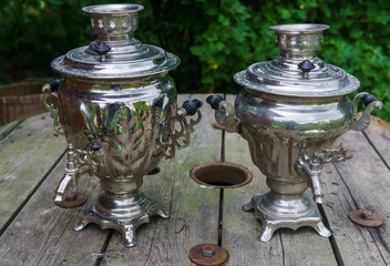 Two old metal samovar for making tea on a wooden table.