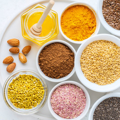 Healthy super food clean eating selection (seeds, powder turmeric, carob, nuts, honey, bee pollen, dried beet)