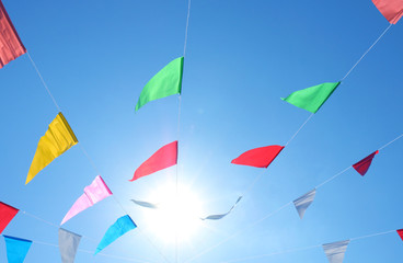 colorful flags on the sky and sunlight background, flags line fancy, colorful flag line and wind sky, festival flag lines on sky in day time, blue sky and colored flags vivid color