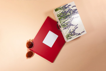 A red envelope, a white box, and sunglasses are laying on a pink surface