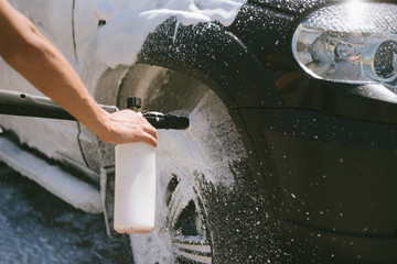 A man sprays a cleaning agent washing a high pressure on the car