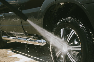 A man washes a car with a high pressure washer