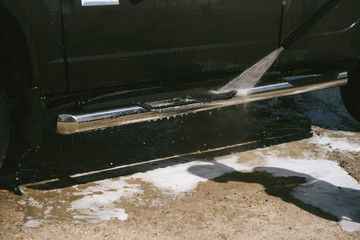 A man washes a car with a high pressure washer