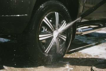A man washes a car with a high pressure washer