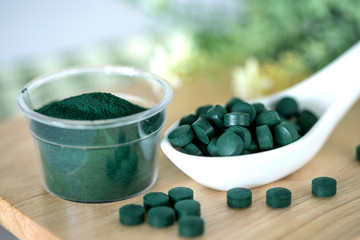 Close up  a spirulina powder  and spirulina pills in spoon , healthy superfood diet and a detox nutrition concept
