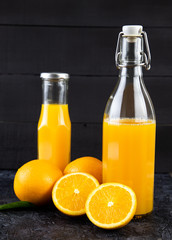 still life photo of orange juice, orange smoothie in glass bottles on wooden background.