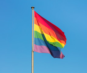 Rainbow flag of the LGBT movement against clear blue sky