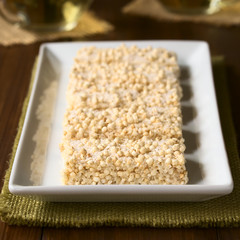 Baked marshmallow, popped quinoa and coconut bars on white plate, photographed with natural light (Selective Focus, Focus on the front of the first bar)