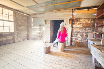 Woman sitting inside an old timber hut on log stools Snowy Mountains