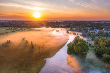 Beautiful ground fog over a small river among grassy meadows in rural areas, early in the morning at dawn.