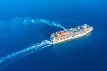 Cruise ship liner with pools, with smoke from the chimney, sails in the blue sea leaving a plume on...