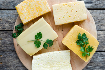 Cheese on a round cutting Board, on an old wooden, rustic background.