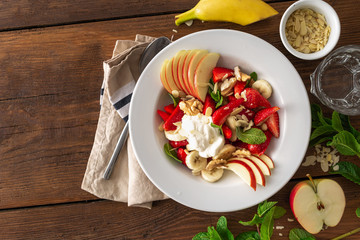 Fruit salad bowl on a wooden table top view. Healthy summer food