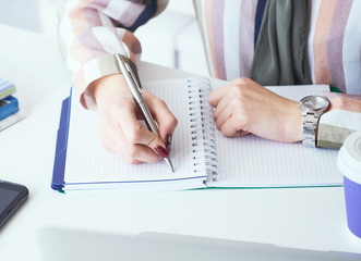 Top view of business woman hands making notes with silver pen in office background. Business...