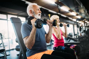Deurstickers Gelukkige senioren die oefeningen doen in de sportschool om fit te blijven © NDABCREATIVITY