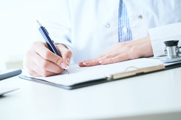 Female medicine doctor hand holding silver pen writing something on clipboard closeup.. Ward round, patient visit check, medical calculation and statistics concept.