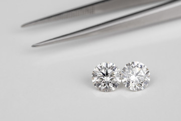 Carat size diamonds compared with tweezers on white isolated