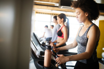 Fototapeta na wymiar Young woman running on a treadmill in health club.