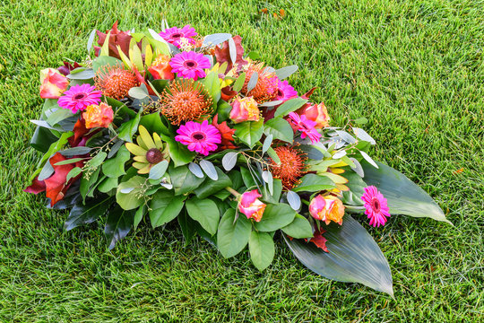 Colorful flower arrangement on green grass field. All Saints flower arrangements, flowers for graveyard and funeral.