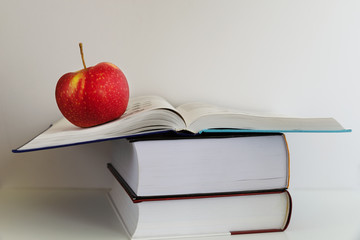 Back to school. Red apple next to books on a white background