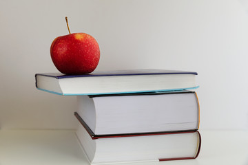 Back to school. Red apple next to books on a white background