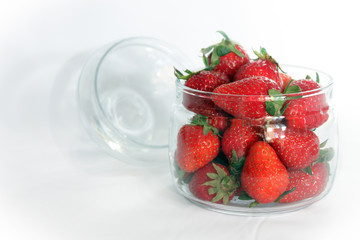 berries ripe red strawberries in a glass open jar on a white background