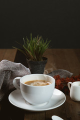 A cup of hot coffee  with coffee bean and milk cup on wooden table