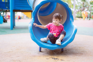 Fototapeta na wymiar Asian baby girl playing slider at playground in the park.