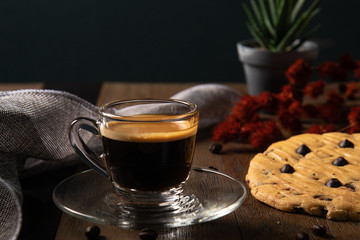 A cup of hot coffee espresso  with coffee bean and homemade cookie on wooden table