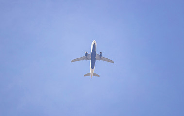 White and blue color commercial airplane against clear sky background. view from below