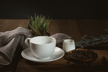 Empty cup of coffee decoration with coffee bean low light mood and tone on wooden table background