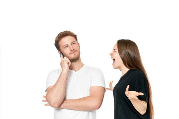 Studio shot of a couple quarreling. Angry woman shouting at the man while he is talking on the phone.