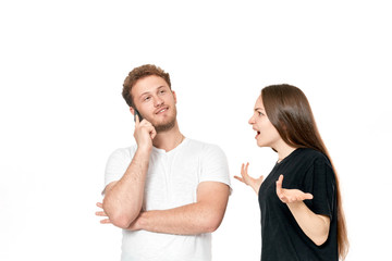 Studio shot of a couple quarreling. Angry woman shouting at the man while he is talking on the phone.